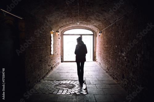 silhouette of young woman in arch of bricks