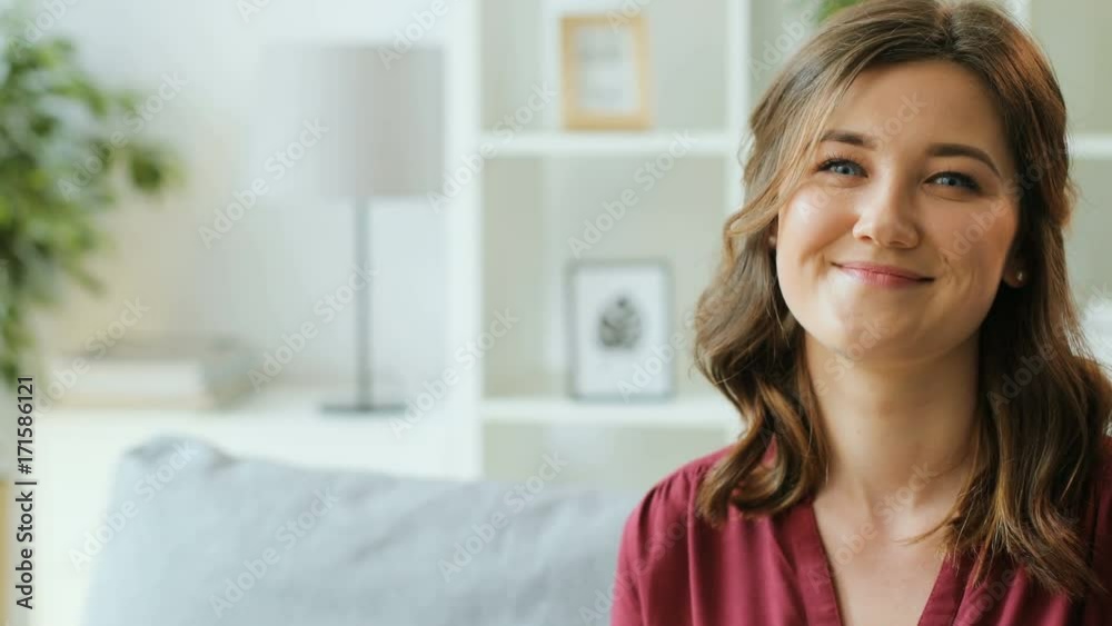 Young smiling woman looking at the camera and waving finger saying no on the living room background. Young smiling woman looking at the camera and waving finger saying no on the living room background.