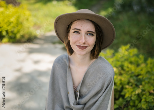 Fashionable young woman wearing in hat and poncho among tropical plants.