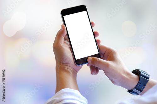 Man hands holding blank screen smartphone with blurred background.