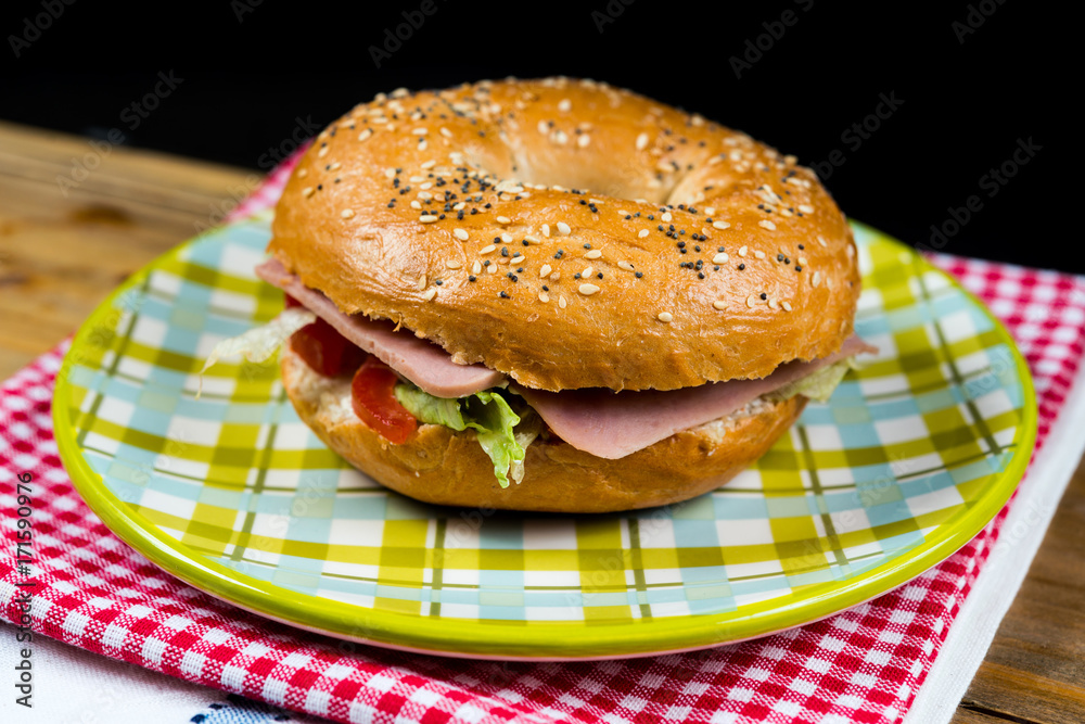Bagel with fresh cheese and fresh lettuce on napkin