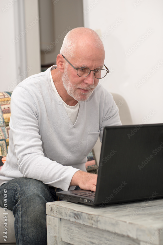 Senior man with notebook sitting in sofa Senior man with notebook sitting in sofa
