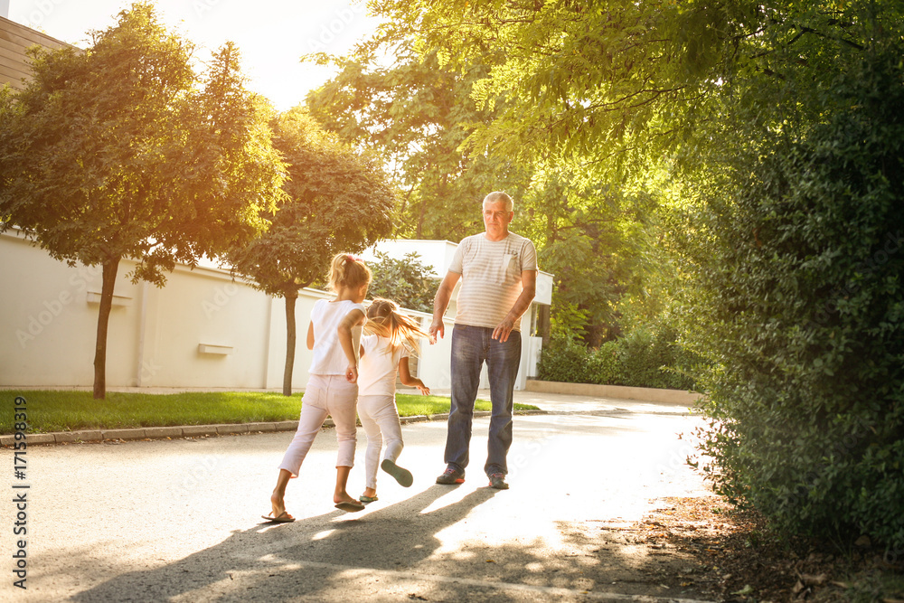 Obraz premium Children walking with their grandfather holding hands.