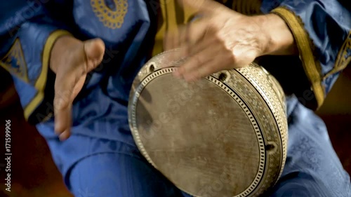 Tight shot of man in Moroccan dress playing arabic doumbek, darbuka, or derbeki photo