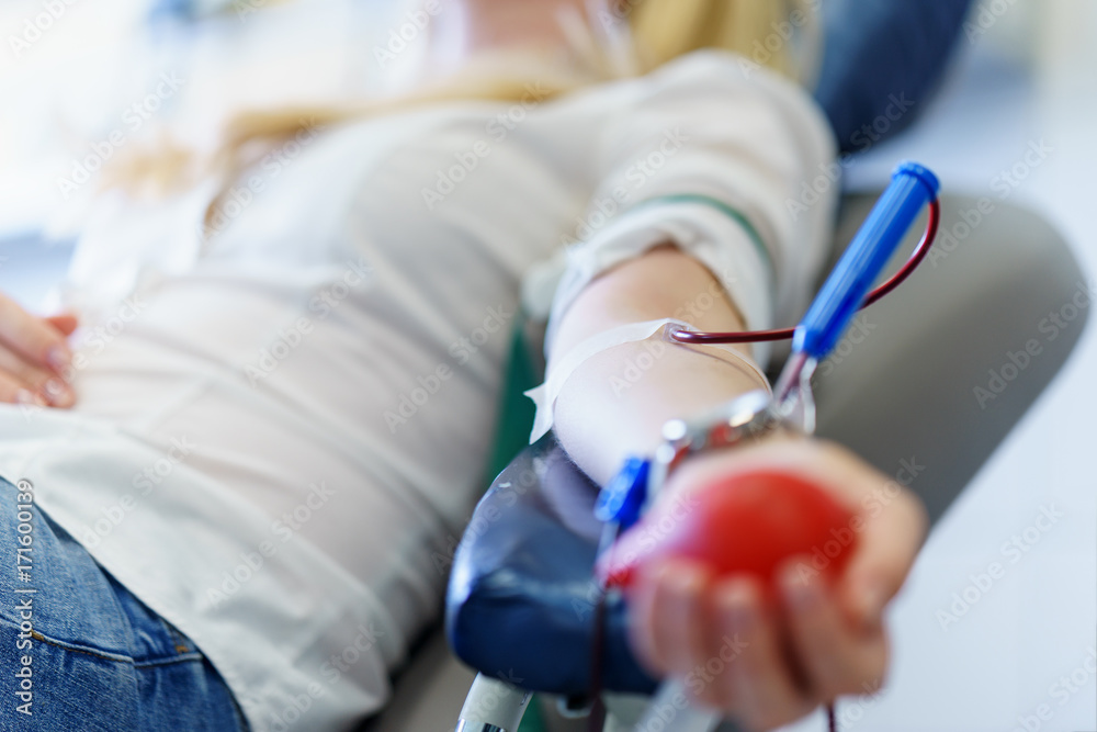 Φωτογραφία young caucasian woman with toy heart in the hand donates blood for saving lives