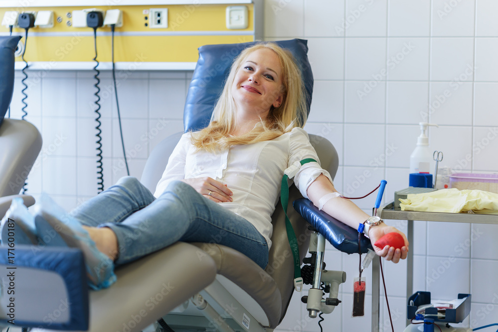 Φωτογραφία young caucasian woman with toy heart in the hand donates blood for saving lives