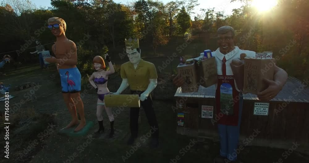 Aerial views of an eccentric’s collection of giant American roadside attractions and oddities like Muffler Man, Brian the Beach Boy, giant apple, crab, the Simpsons riding a train around Santa Claus p