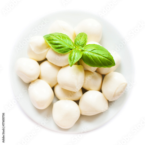 Bowl of small mozzarella balls isolated on white background with basil leaves,  close up, top view.
