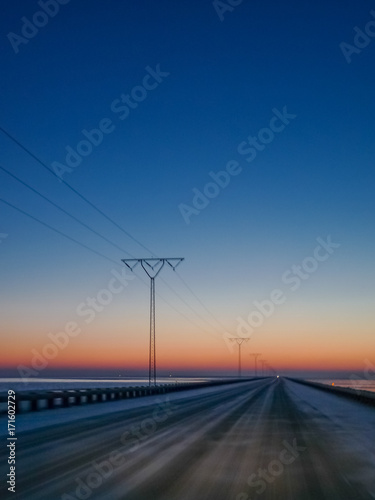 Highway in the sunrise on a cold winter morning, power line beside