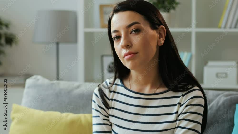 Portrait of attractive woman turning and smiling at the camera, sitting on the sofa in the living room at home. Portrait of attractive woman turning and smiling at the camera, sitting on the sofa in the living room at home.
