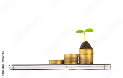 smart phone with stack of coins and seedling on top. business finance concept photo