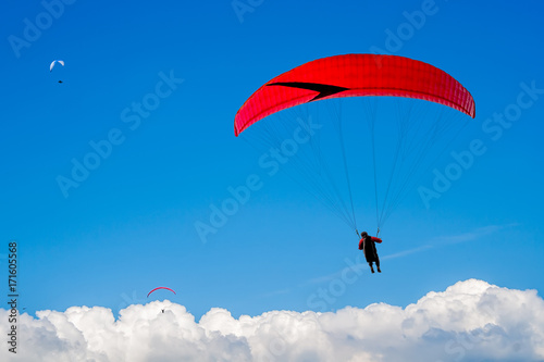 The paraglider hovers in the sky high above the clouds