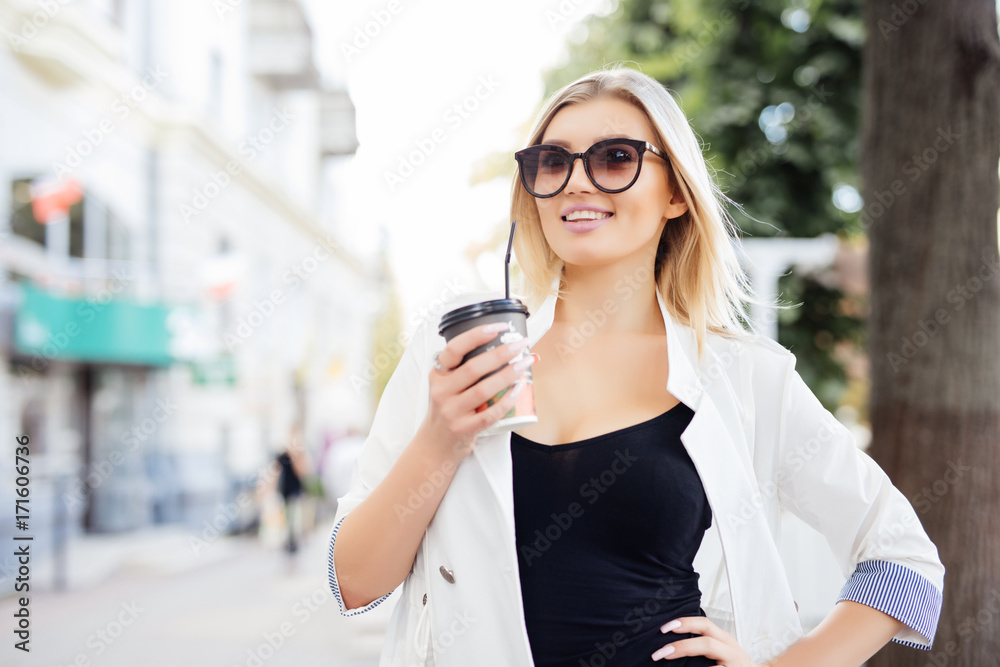 Beautiful girl standing on the street with coffee and glasses. Beautiful girl standing on the street with coffee and glasses.