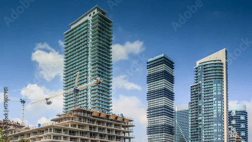 Timelapse of constraction site and residential high rise buildings with moving white clouds in blue sky, Toronto 