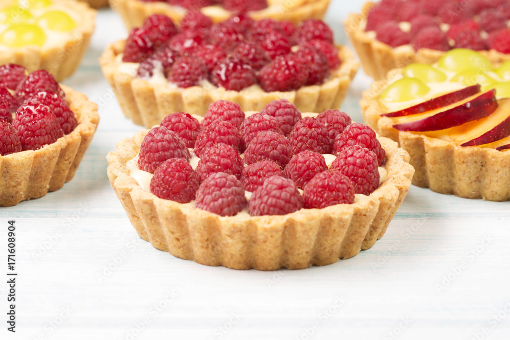 Tart with custard and berries, raspberry, light blue background, horizontal, selective focus Tart with custard and berries, raspberry, light blue background, horizontal, selective focus