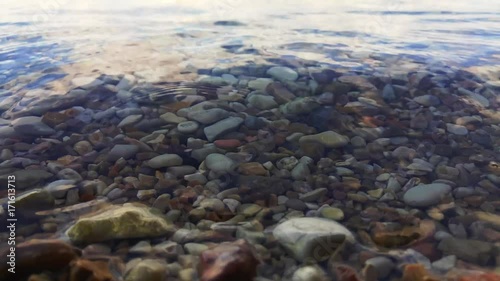 Relaxing scene of waves and gravels in shallow sea water surface