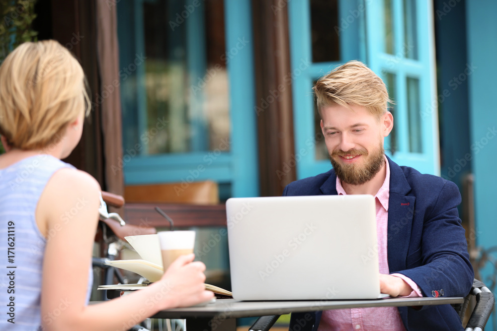 Young blogger with with woman sitting in cafe, outdoors Young blogger with with woman sitting in cafe, outdoors