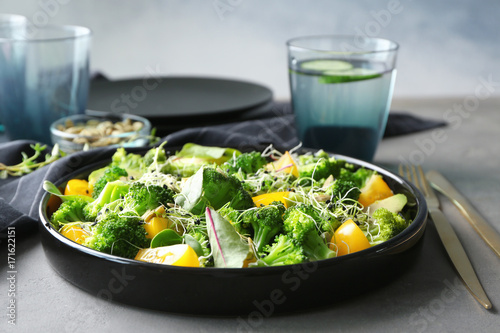 Superfood salad with broccoli and yellow tomato on grey table