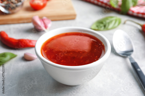 Composition with chili sauce in bowl on table