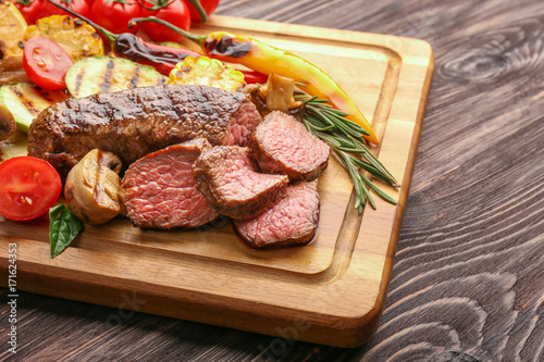 Tasty meat with vegetables on wooden board