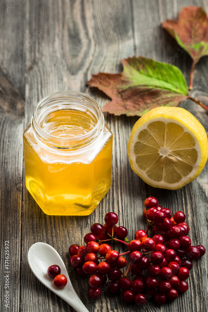 Fototapeta Honey, lemon and berries on wooden table. Homemade remedies. Selective focus.
