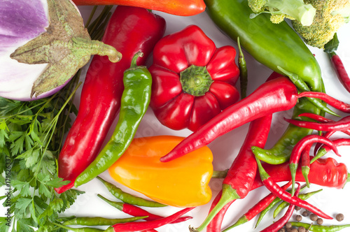 Harvest of different peppers and vegetables on a white background photo