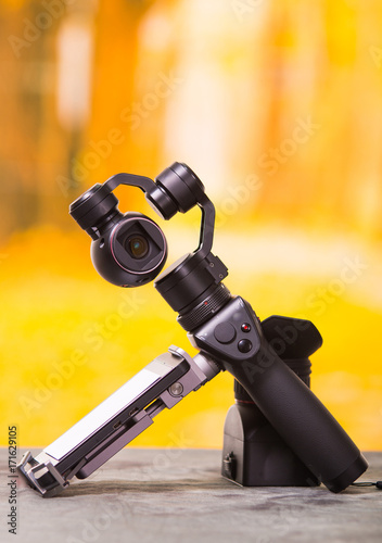 Osmo Mobile gimbal, new generation of electronic stabilizer over a wooden table in a blurred forest background photo