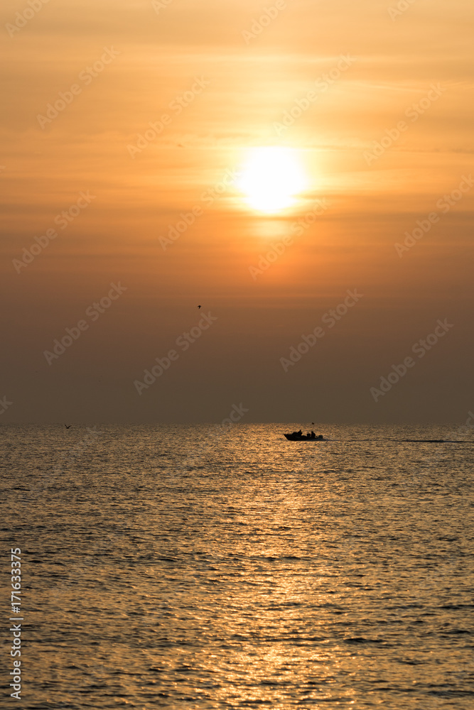 portrait of sunrise over the mediterranean sea with patrol boat below the sun