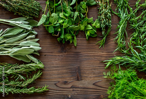fresh herbs and greenery for spices and cooking on wooden desk background top view mock up