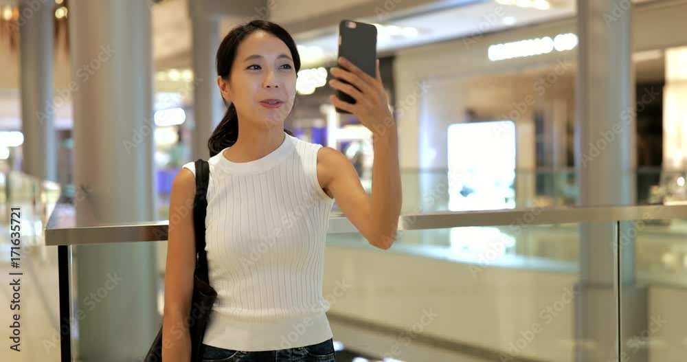 Woman making a video call on cellphone in shopping mall Woman making a video call on cellphone in shopping mall
