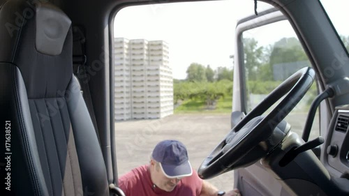 Truck driver climbs up to cab, sits down behind the wheel and shuts door in daylight interior, summer day. Hand-held slow motion 4K recorded at 60fps.