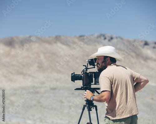 Filmmaker using digital cinema camera, composing shot, desert in distance photo