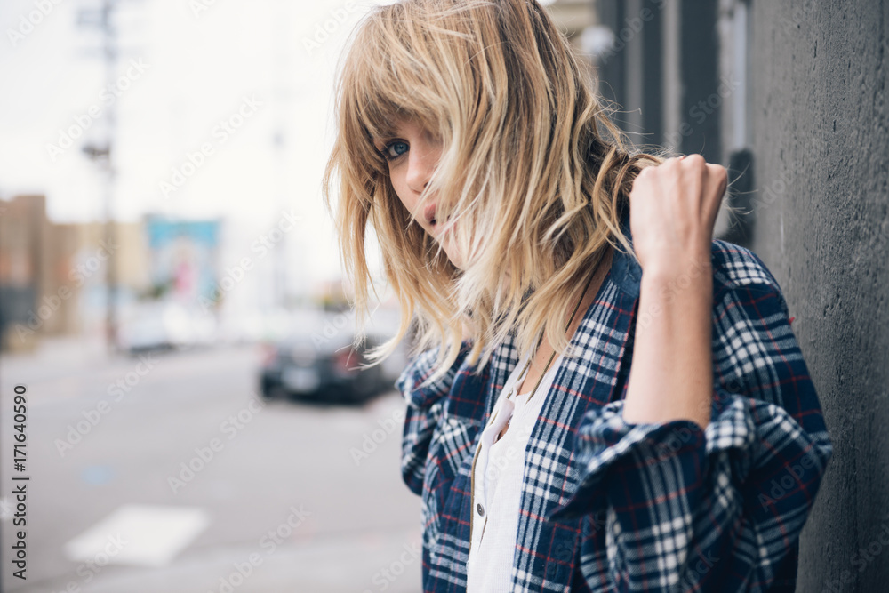 Young woman adjusting her shirt while hair covers her face Young woman adjusting her shirt while hair covers her face