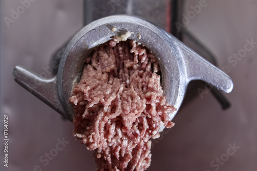 Closeup of minced raw meat coming out from grinder 