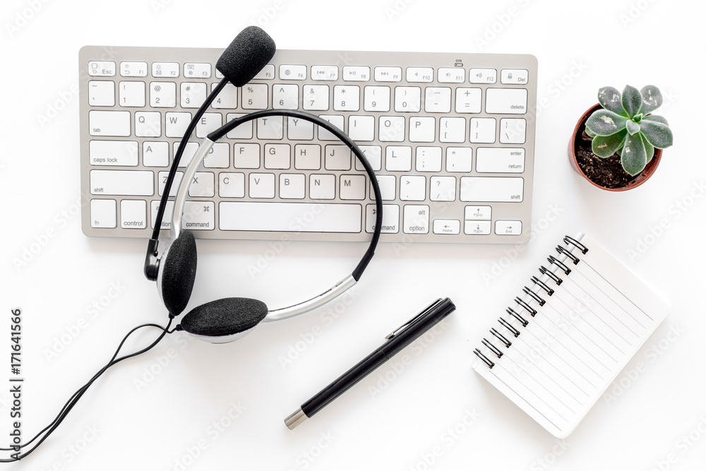 Workplace in call center. Headphones on keyboard and notebook on white background top view Workplace in call center. Headphones on keyboard and notebook on white background top view