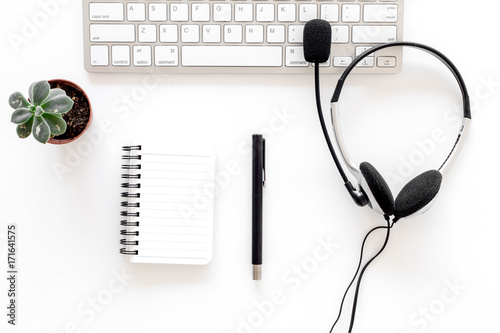 Workplace in call center. Headphones on keyboard and notebook on white background top view