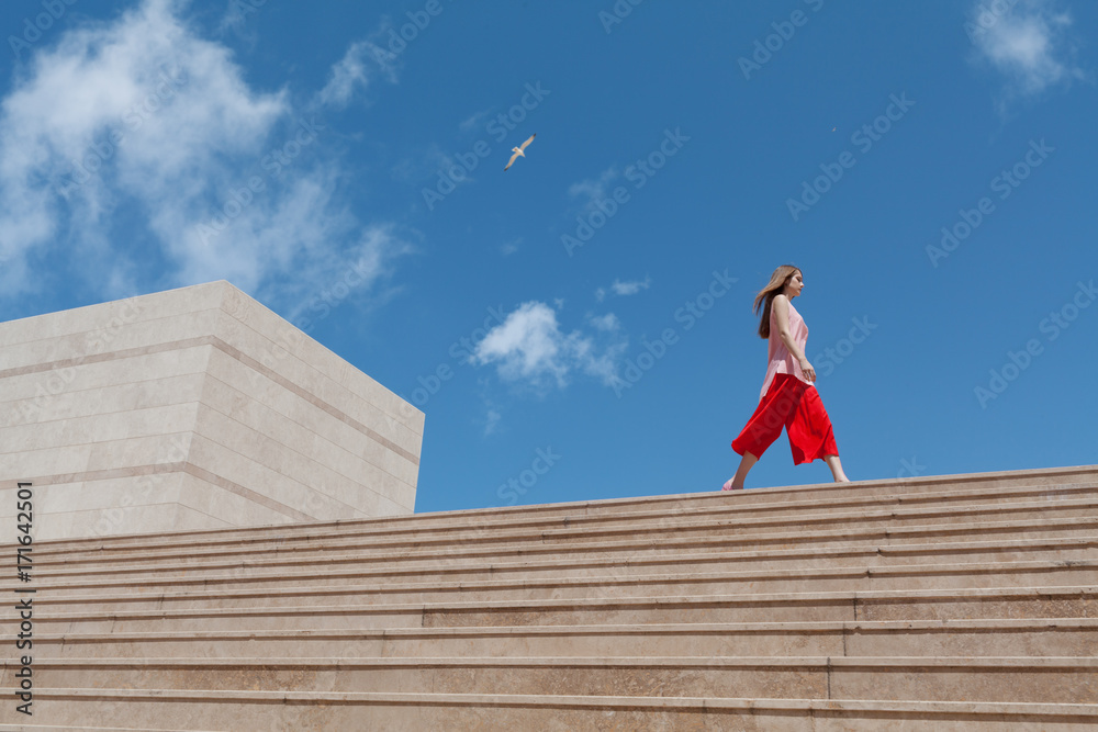 Young woman walking along stairs Young woman walking along stairs