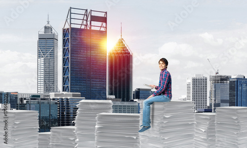 Attractive man sitting on pile of paper documents. © adam121