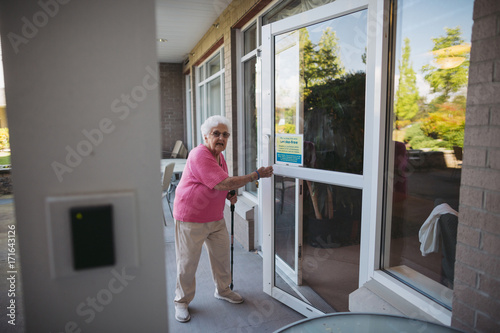 Senior woman opoening door with no smoking sign on it