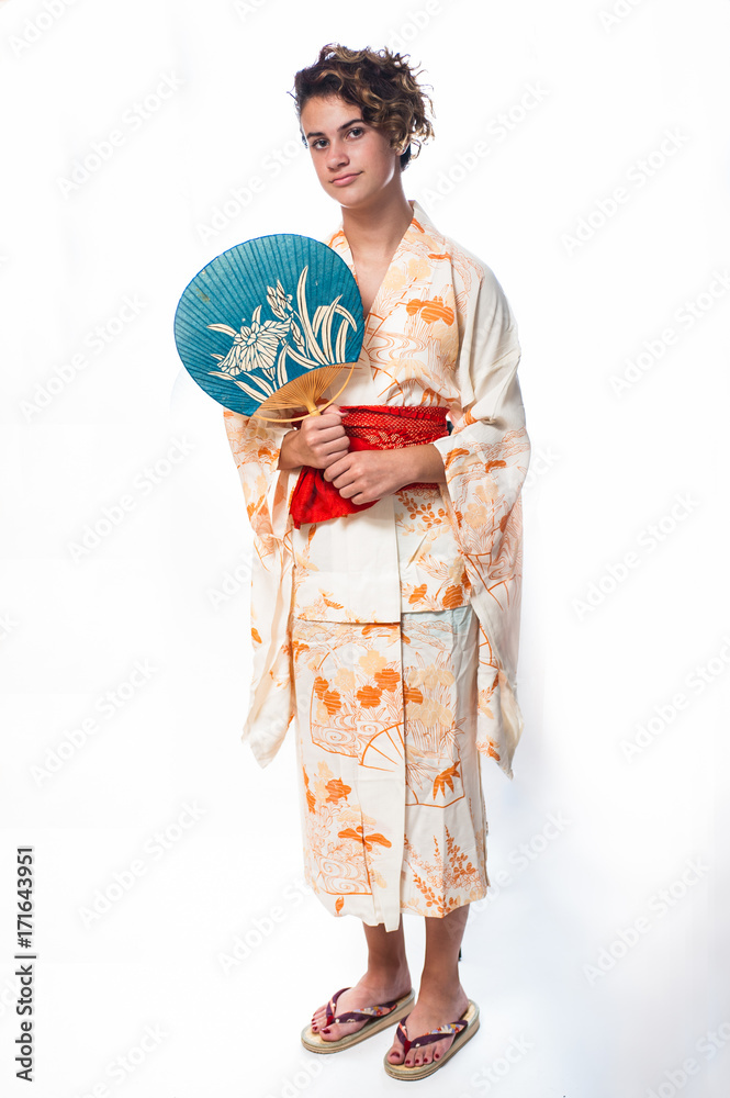 Teen age girl dressed in casual Japanese Yukata kimono holding paper fan on shoulder. Teen age girl dressed in casual Japanese Yukata kimono holding paper fan on shoulder.