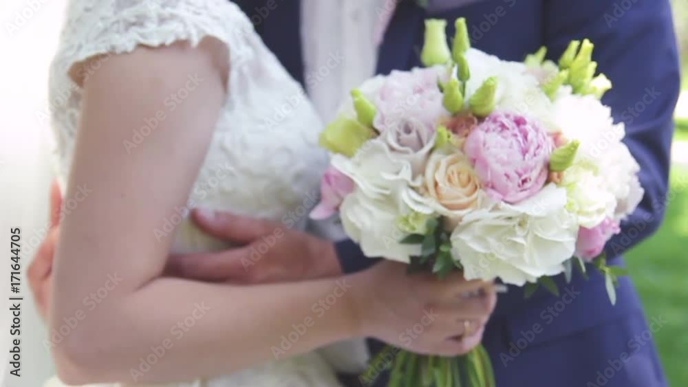 beautiful bride in a white wedding dress is kissing with the groom in a suit outdoors in a park in summer beautiful bride in a white wedding dress is kissing with the groom in a suit outdoors in a park in summer
