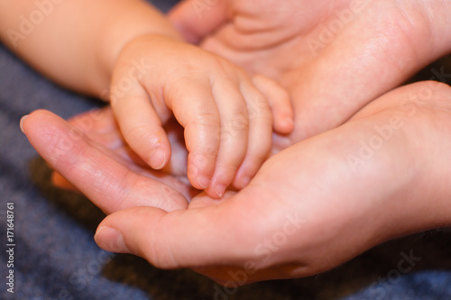 Die Hand eines Babys liegt in den Händen der Mutter