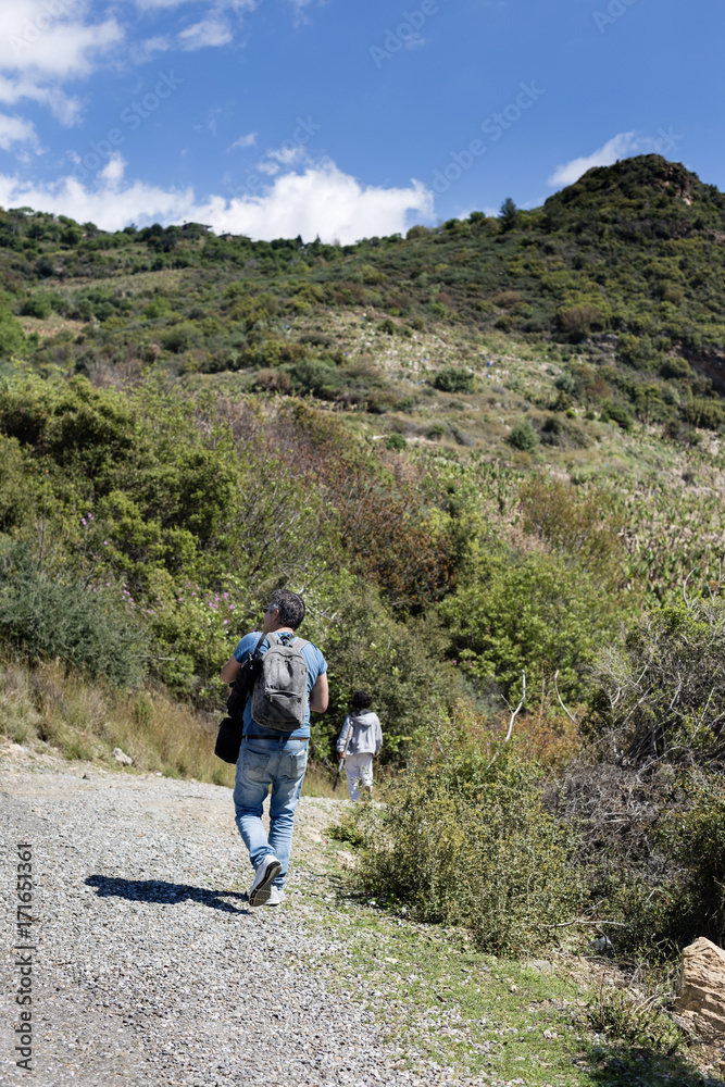 Tourist man with backpack and tripod and small boy trekking in mountain