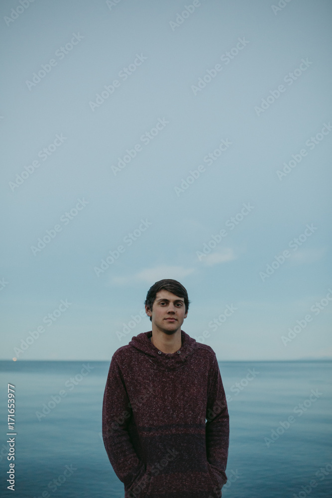 Portrait of young caucasian boy standing near water on beach Portrait of young caucasian boy standing near water on beach