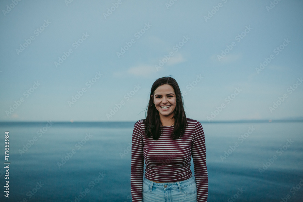 Portrait of young caucasian girl standing near water on beach
