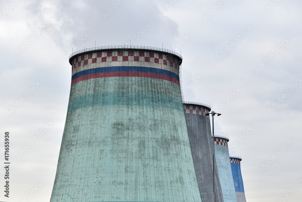 Large pipes of the heat station smoke against the sky with clouds Large pipes of the heat station smoke against the sky with clouds