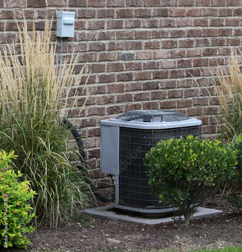 Air Conditioner Near House Surrounded By Shrubs