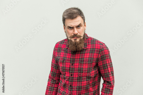 Handsome businessman with beard and handlebar mustache looking at camera with angry face