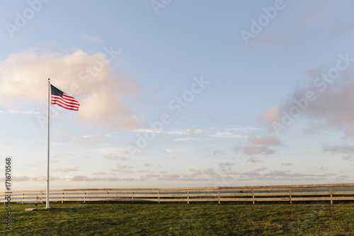 American flag on grassy landscape against cloudy sky