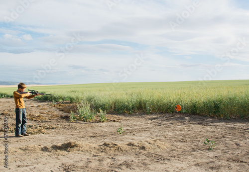 boy aiming bb gun at target in field photo